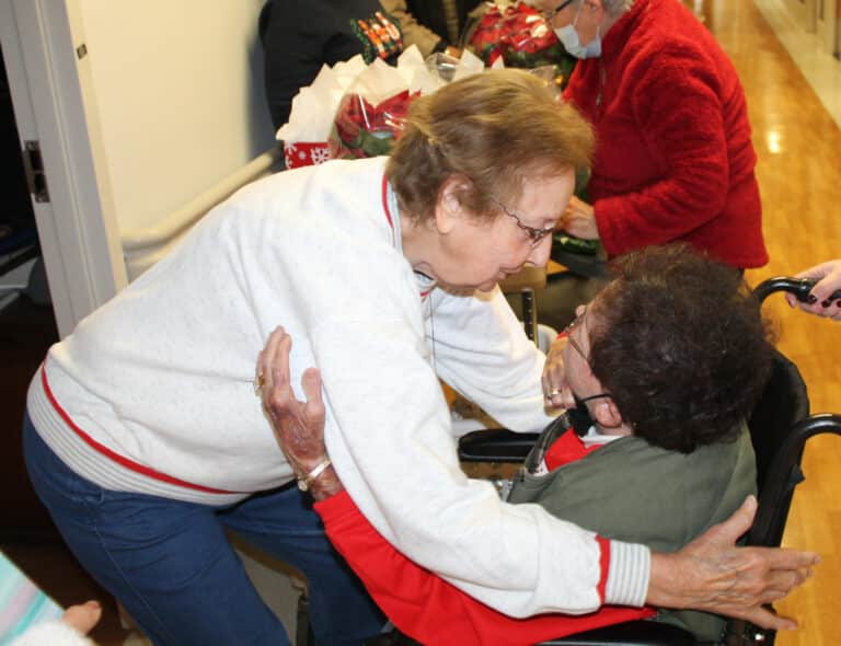 Sister Susan Mary Mudd hugs Associate Phyllis Troutman in the hallway. They are both from Marion County, Ky.