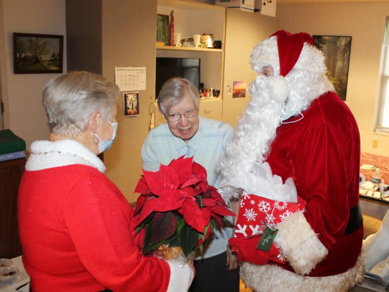 Sister Amanda Rose Mahoney is overjoyed to receive her poinsettia from Santa and Mrs. Claus.
