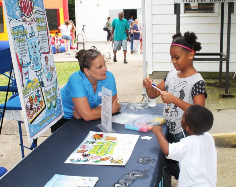 This volunteer with the Louisville Water Co., explains to these children the importance of drinking water and brushing your teeth.