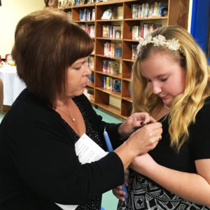 Julie Foster, left, assistant leader of Y-DOSA in Whitesville, places the Y-DOSA pin on her daughter Maggie.