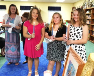 The three newest Y-DOSA members hold their candles during the ceremony. From left are Taylor Pedley, Maggie Foster and MaKenna Greenwell. Doreen Abbott and Julie Foster confer in the background.