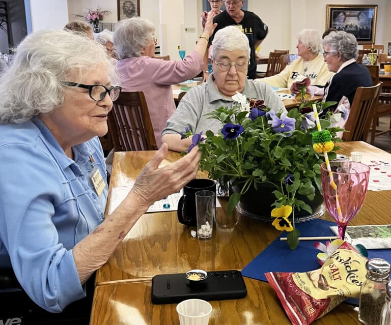 Sister Pat Rhoten, left, enjoys the flowers on the table, while Sister Ann McGrew focuses on her bingo card.