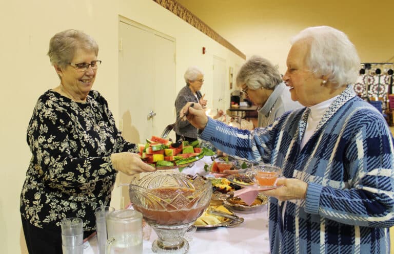 Gertie Frey, right, helps herself to a slice of watermelon offered by Sister Betsy Moyer. Buttermilk cookies and watermelon were served in honor of the first meal the Ursuline Sisters had when they arrived at Maple Mount in 1874.