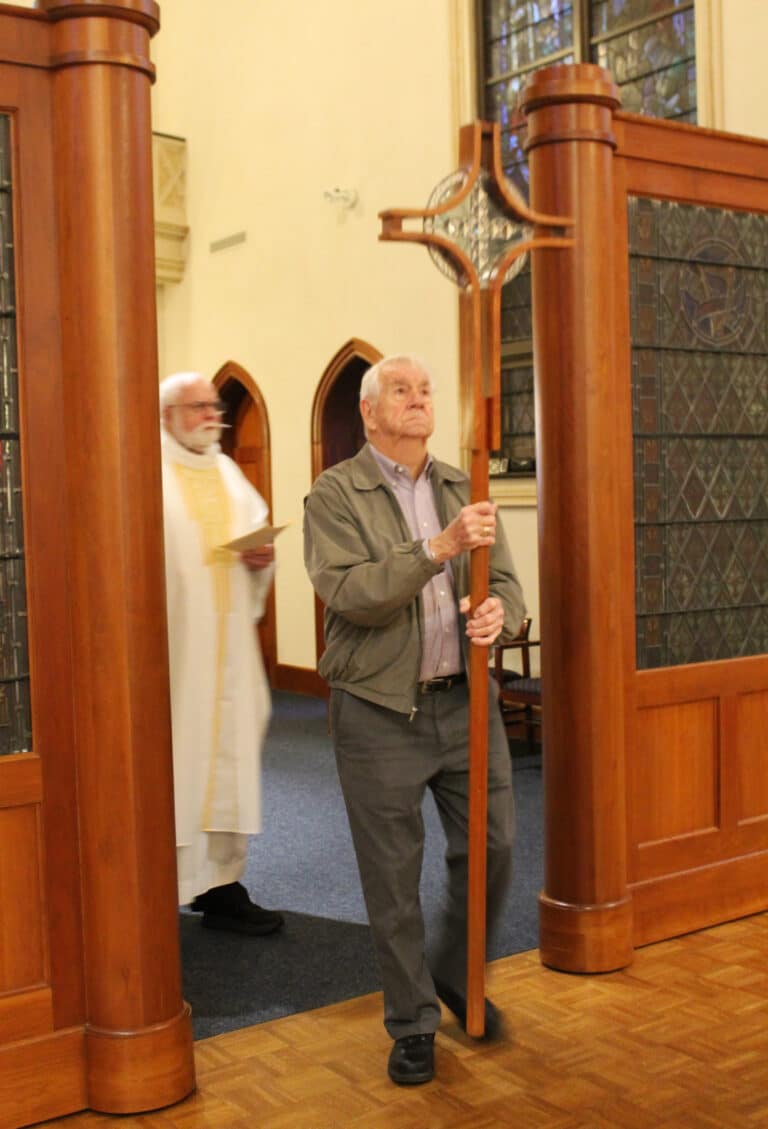 Ursuline Associate Mike Sullivan carries in the processional cross as Father Ray Goetz follows him to begin Mass.