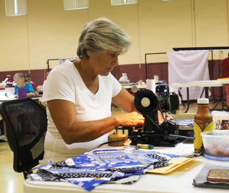 Marilyn Adkins, of Sacramento, Ky., sews one of the pieces of UK fabric she just cut while taking part in the “Sit and Sew” in the gymnasium. The pieces are part of a spin around quilt she is making for her son, who graduated from the University of Kentucky in the spring. “He’ll cover up with it on the couch,” she said.
