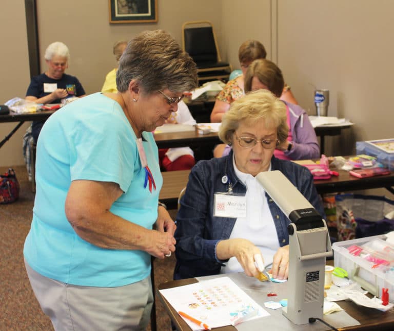 Margaret Scott, left, of Island, Ky., one of the coordinators of the Runaway Quilters, gives some advice to Marilyn Collins of Albion, Ill., during her class on how to make “Not Your Grandmother’s Flower Garden,” using the English paper piecing method.