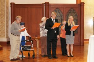 The new associates, from left, Victor Monaco, Ron Bornander, and Cindy Bornander, recite their commitments as their contact companions place their hands on the associate's shoulder.