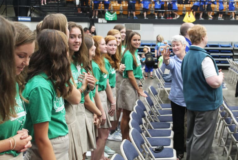 Sister Pam Mueller waves to some Owensboro Catholic High School students during the sign of peace.