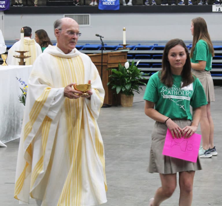 Father Jerry Riney, an Ursuline Associate, follows a volunteer to his communion station.