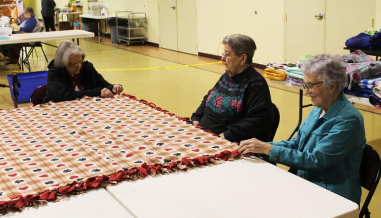 Sister Catherine Barber, left, gets instruction on blanket making from Sister Rose Jean Powers, center, as Sister Ann Patrice Cecil works on the opposite corner.