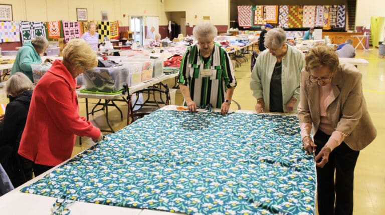 Ursuline Associates Carol Hill, left, of Leitchfield, Ky., and Suzanne Reiss, of Lanesville, Ind., second from left, join Sister Emma Ann Munsterman and Susan Mary Mudd, right, to cut strips in fabric to be tied together and make a blanket. The volunteers worked in Maple Hall, where the Quilting Friends were also sewing.