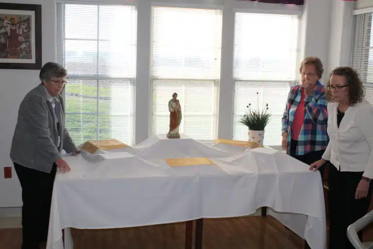 Sister Margaret Ann Aull, left, and Sister Susan Mary Mudd, center, join Ashley Wilkerson, the activities coordinator for the Sisters in the Villa, in setting up Saint Joseph’s Table. Sister Margaret Ann Aull, left, and Sister Susan Mary Mudd, center, join Ashley Wilkerson, the activities coordinator for the Sisters in the Villa, in setting up Saint Joseph’s Table.