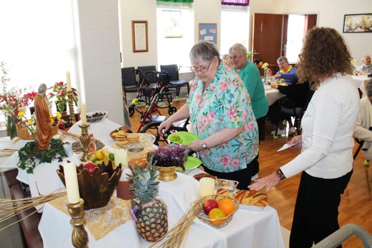 Sister Joyce Marie Cecil, center, gets ready to help herself to some of the treats on the table, as Sister Karla Kaelin, in the background, approaches the table.