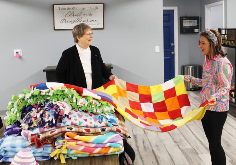 Angel Welsh, right, spreads out a blanket with Sister Amelia Stenger on March 22, 2024. All of the blankets will be given to women served by the shelter when they move out.