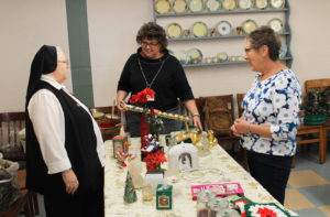 Ursuline Associate Martha Alle, center, director of Finance for the Ursuline Sisters, engages Sister Catherine Marie Lauterwasser, left, about some German Christmas items, as Associate Stephanie Render looks on.