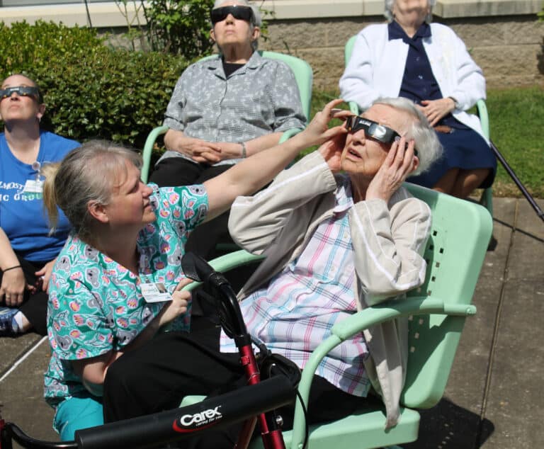 Kimberly Teague, a caregiver with Almost Family, helps Sister Marie Bosco Wathen adjust her glasses.