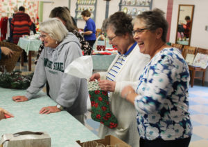 Ursuline Associate Coreen Moore, left, who was helping with the sale, laughs with Sister Paul Marie Greenwell, center, and Associate Stephanie Render.