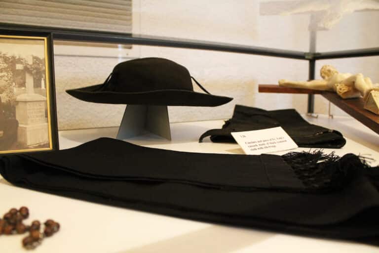 Pictured here are Father Volk’s hat, the cincture he wore around his neck, and a piece of his cassock made from black common cloth and silk fringe.