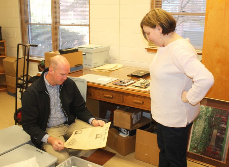 Tim Tomes looks at a loose copy of The Record as Heidi Taylor-Caudill looks on. There were four large bins of loose copies of The Record, the Guardian and The Catholic Advocate.