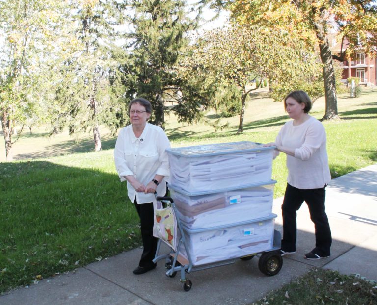 Sister Amelia Stenger and Heidi Taylor-Caudill roll out three of the four large bins of historic Catholic newspapers that were being donated to the Archdiocese of Louisville.