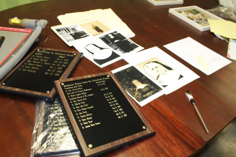 Plaques and photos rest on the work station in the basement of St. Elizabeth Parish. The plaque featuring the women religious will have to be redone, since more names have been found. Plaques and photos rest on the work station in the basement of St. Elizabeth Parish. The plaque featuring the women religious will have to be redone, since more names have been found.