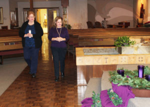Ursuline Associates Karen De Sosa, left, and Jennifer Kaminski bring the first candle to the Advent wreath.