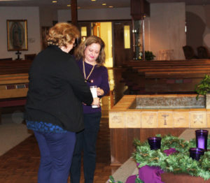Jennifer Kaminski lights the candle that Karen De Sosa placed on the Advent wreath.