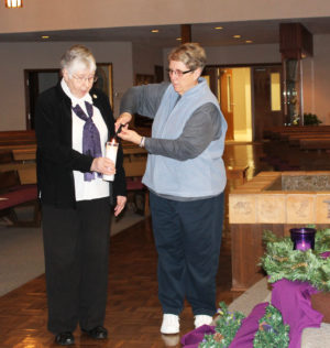 Ursuline Sister Betsy Moyer, right, lights the candle held by Ursuline Sister Ruth Gehres.