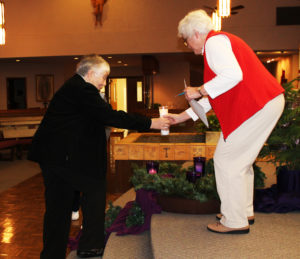 Sister Ruth Gehres hands the lighted candle to Marian Bennett to place on the Advent wreath.
