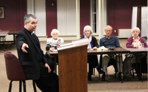 Bishop Medley tells those present that it wasn’t until the fourth century that leaders of the Church gave Mary the Greek name “Theotokos,” which means “God-bearer.” Listening from left are Ursuline Sister Mary Matthias Ward, Emily DeMoor, Jim Sullivan and Ursuline Sister Eva Boone.