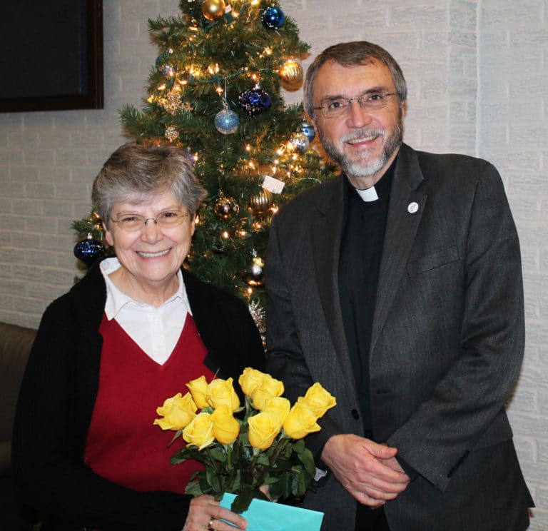 Father Larry Hostetter gathers with Sister Cheryl as she holds beautiful flowers she received.