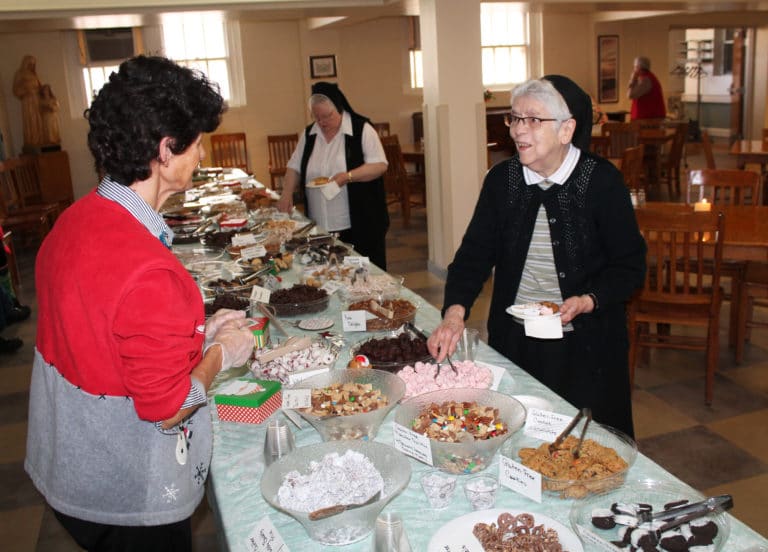 Sister Michael Ann Monaghan is all smiles as she loads her plate while talking with Center employee Janie Walther. The Center staff made all those goodies. Getting in line next is Sister Catherine Marie Lauterwasser.