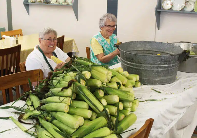 Sister Karla Kaelin, left, and Sister Ann Patrice Cecil work on their pile of corn. Sister Karla Kaelin, left, and Sister Ann Patrice Cecil work on their pile of corn.