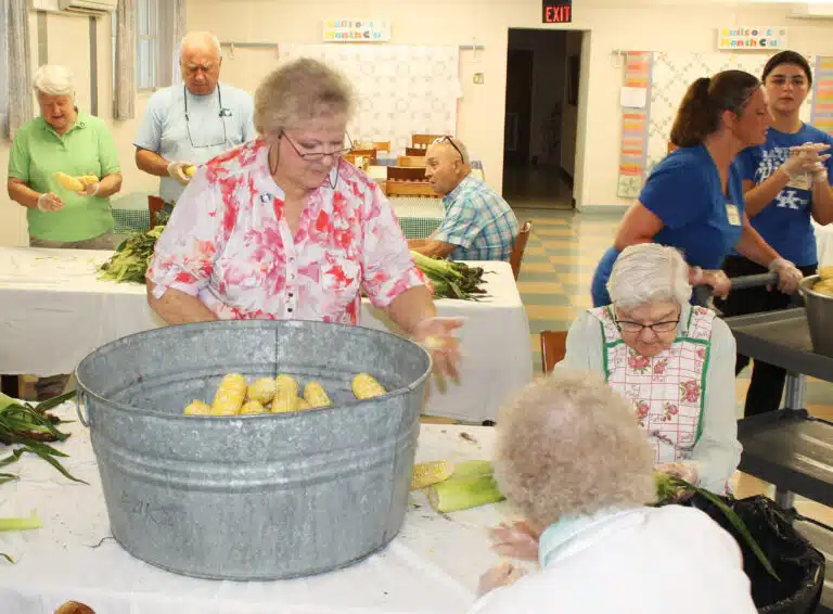 Ursuline Associate Suzanne Reiss, center, fills a bucket with cleaned corn, as Sister George Mary Hagan works on shucking. Ursuline Associate Suzanne Reiss, center, fills a bucket with cleaned corn, as Sister George Mary Hagan works on shucking.