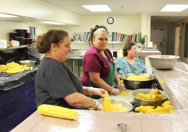 Food Service staff, from left, Amanda Geary, Trish Durham and Charlotte Stelmach, cut corn off the cob to bag and store. Food Service staff, from left, Amanda Geary, Trish Durham and Charlotte Stelmach, cut corn off the cob to bag and store.