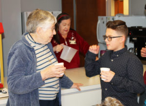 Sister Ruth Gehres takes a water break with one of the square dancers, who seems to be explaining his dance techniques. In the background, Debbie Dugger, activities director, fills drink cups.