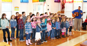 The K-4th graders sing “Peace is Flowing Like a River” under the direction of their music teacher, Brian Snyder, right.