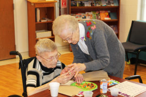 Sister Alfreda Malone, right, helps Sister Rosalin Thieneman with her cupcake during the party.