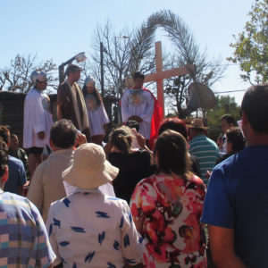 Outside the church, the people gather behind the truck-drawn flatbed carrying the dramatization of the stations.