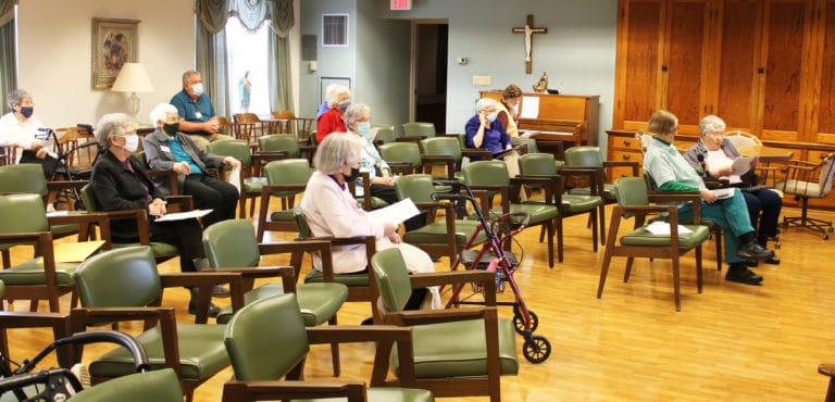 Sister Ruth Gehres, right, reads through her presentation as Sisters following along on the tv screen. Next to Sister Ruth is Sister Rebecca White.