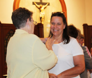 New Associate Tina Wolken smiles as Sister Sharon Sullivan places her Associate pin on her following her commitment.