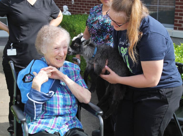 Sister Marie Carol Cecil enjoys some kisses from Elvis the dwarf goat, who was held by Donna Nelson, a home health aide with Almost Family.