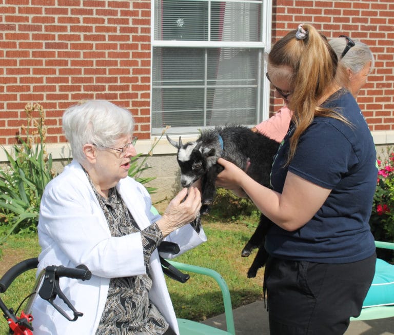Sister Eva Boone gets an introduction to Elvis the goat while Donna Nelson holds him.