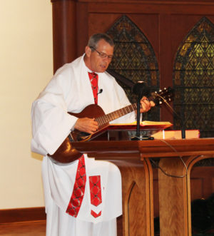 Father Ray Clark, the presider at Mass, played the guitar during his homily to emphasize being aware of the presence of God in the Eucharist.