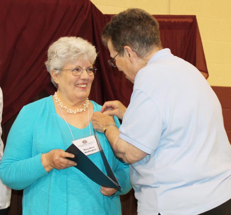 Sister Sharon Sullivan, right, places the Associate pin on Mary Alice Wethington. The two served together for many years at Brescia University.