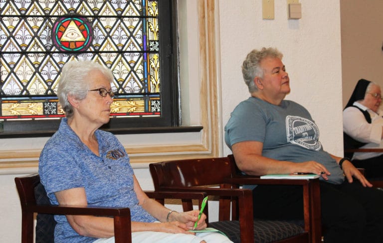 Sister Barbara Jean Head, left, and Sister Martha Keller listen intently to Father Hensell.