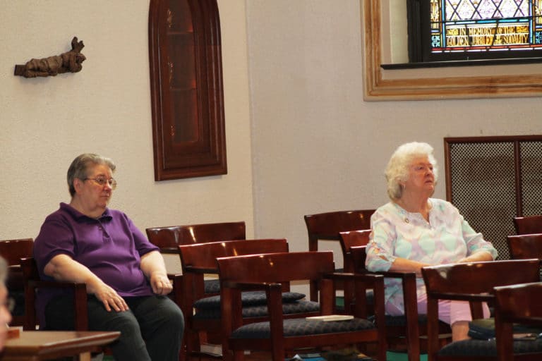 Sister Rose Jean Powers, left, and Sister Vivian Bowles listen to Father Hensell’s talk. The two served together at Brescia University for many years.