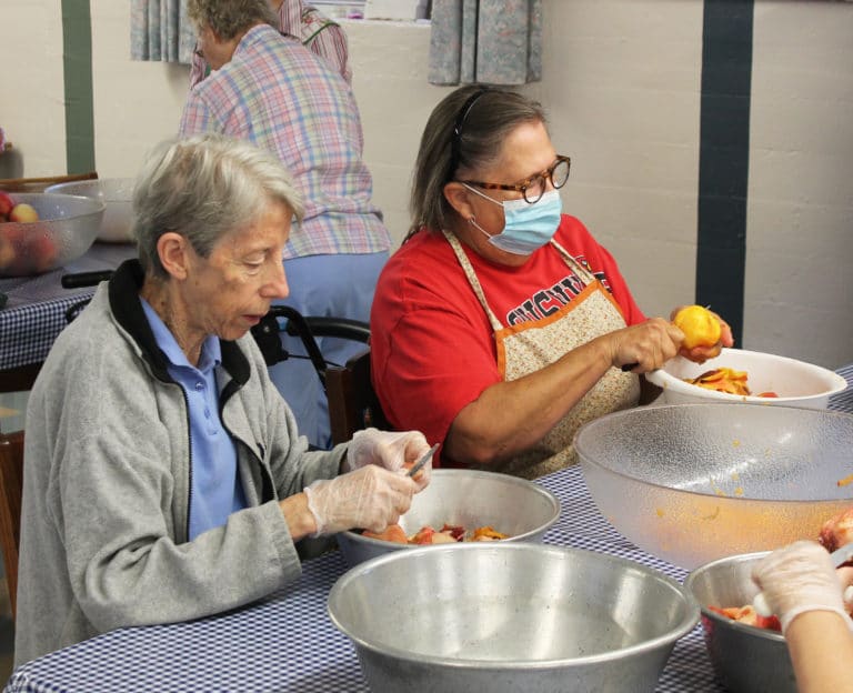 Sister Maureen O’Neill, left, and Rosemary Miller make quite a “pare” as they peel their peaches.