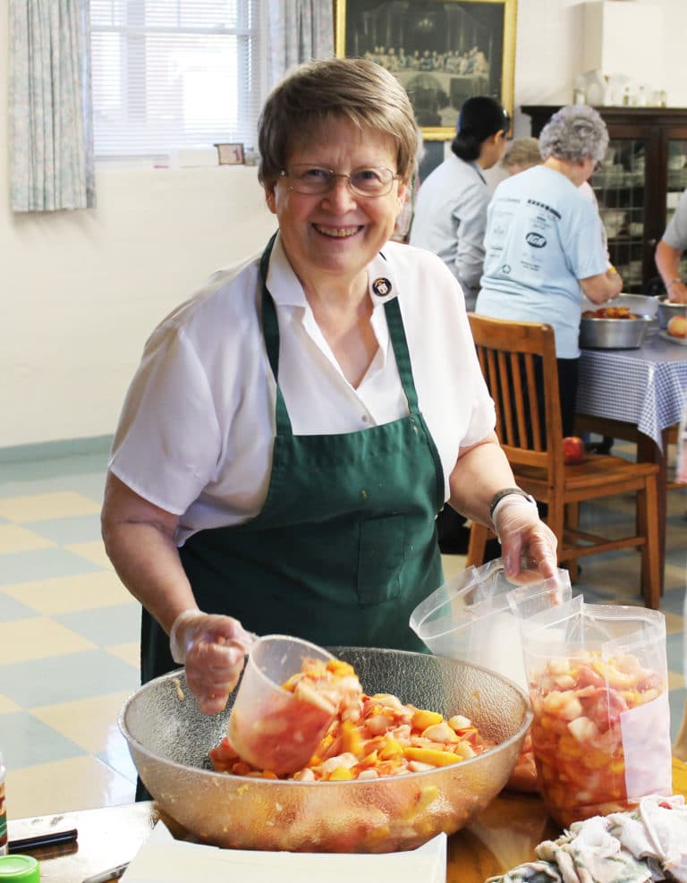 Sister Amelia Stenger earns the nickname “Scoop” as she fills plastic bags with sliced peaches.