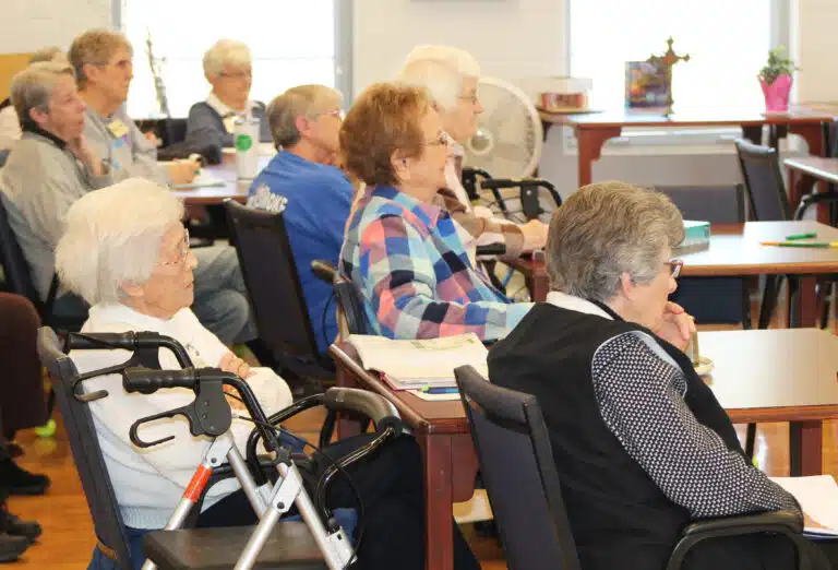 In the foreground, Sisters Elaine Burke, left, Susan Mary Mudd, center, and Margaret Ann Aull listen to Father Burke say, “You have what it takes to leverage faith, hope and charity. Rely on God to do the heavy lifting.” In the background, from left, are Sisters Maureen O’Neill, Betsy Moyer, Cecelia Joseph Olinger, Emma Anne Munsterman and Mary Matthias Ward. In the foreground, Sisters Elaine Burke, left, Susan Mary Mudd, center, and Margaret Ann Aull listen to Father Burke say, “You have what it takes to leverage faith, hope and charity. Rely on God to do the heavy lifting.” In the background, from left, are Sisters Maureen O’Neill, Betsy Moyer, Cecelia Joseph Olinger, Emma Anne Munsterman and Mary Matthias Ward.